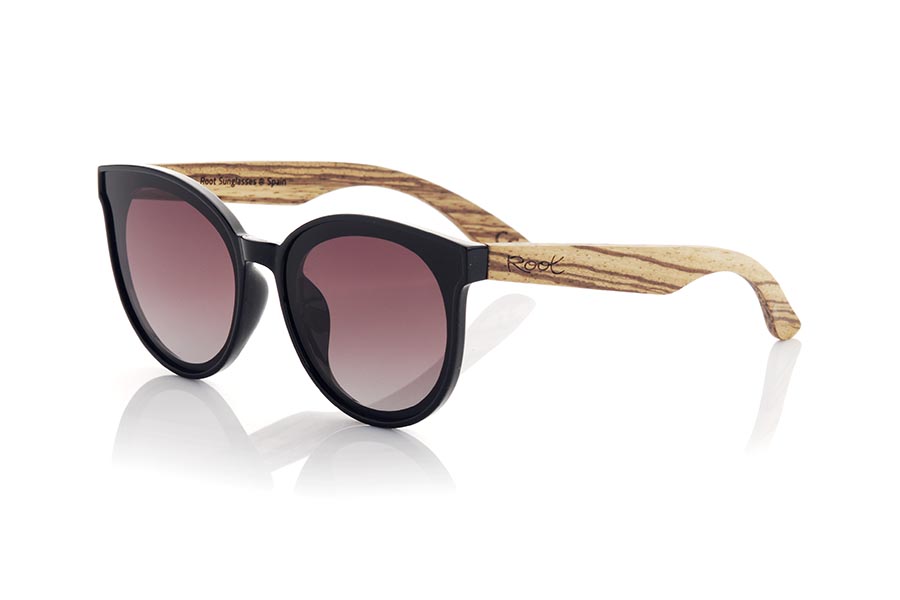 Wood eyewear of Walnut SOPHIA. Sophia sunglasses are the perfect accessory to add a touch of style to your looks at all times. With a rounded frame in satin black, the lenses are mounted on the frame, giving it a retro and modern touch at the same time. The wide temples in grained walnut make a harmonious contrast to the frame. This model is a very attractive female model, although some more daring men will also want to have one. It is available in two lens colors so you can choose the one that best suits your needs and style. Do not hesitate to get some Sophia glasses to protect your eyes from the sun with style. Front measurement approx: 142x55mm for Wholesale & Retail | Root Sunglasses® 